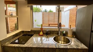 A modern kitchen with a built-in stove, a stainless steel sink, and a window overlooking a wooden deck.