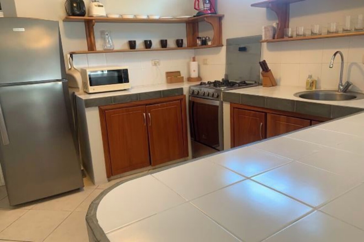Una cocina con refrigerador, microondas, estufa y armarios de madera.