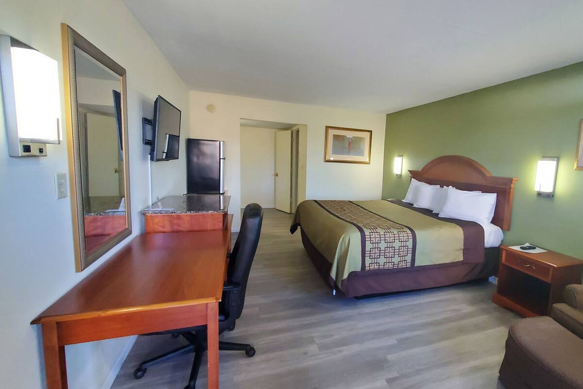A hotel room with a bed, desk, chair, and a small couch.