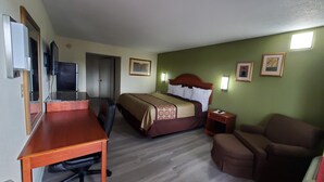Una habitación de hotel con cama, escritorio, silla y televisión.