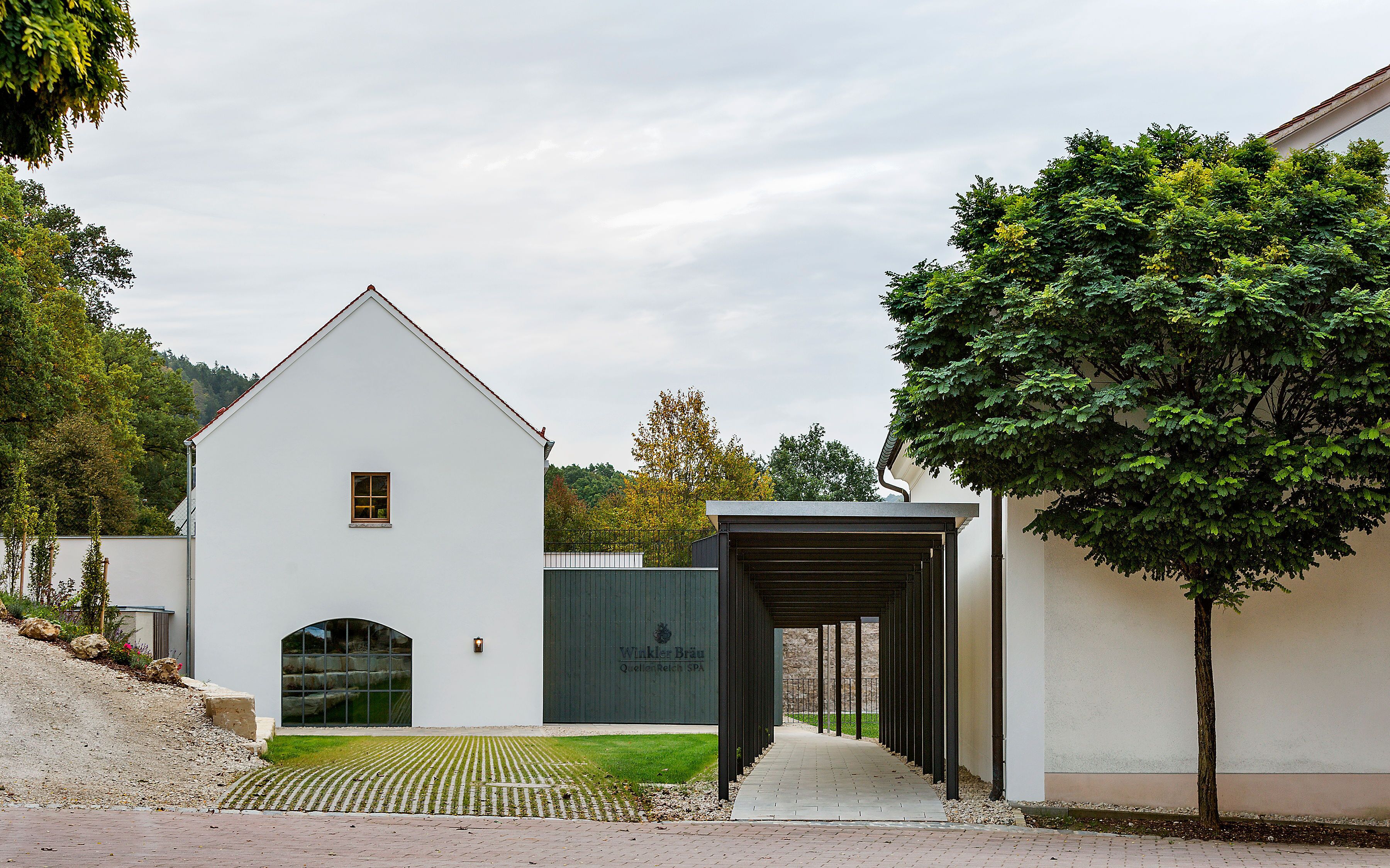 Un bâtiment moderne à la façade blanche, doté d’une petite fenêtre et d’une entrée abritée.