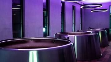 A row of large, metallic cylindrical containers in a modern interior with purple lighting.