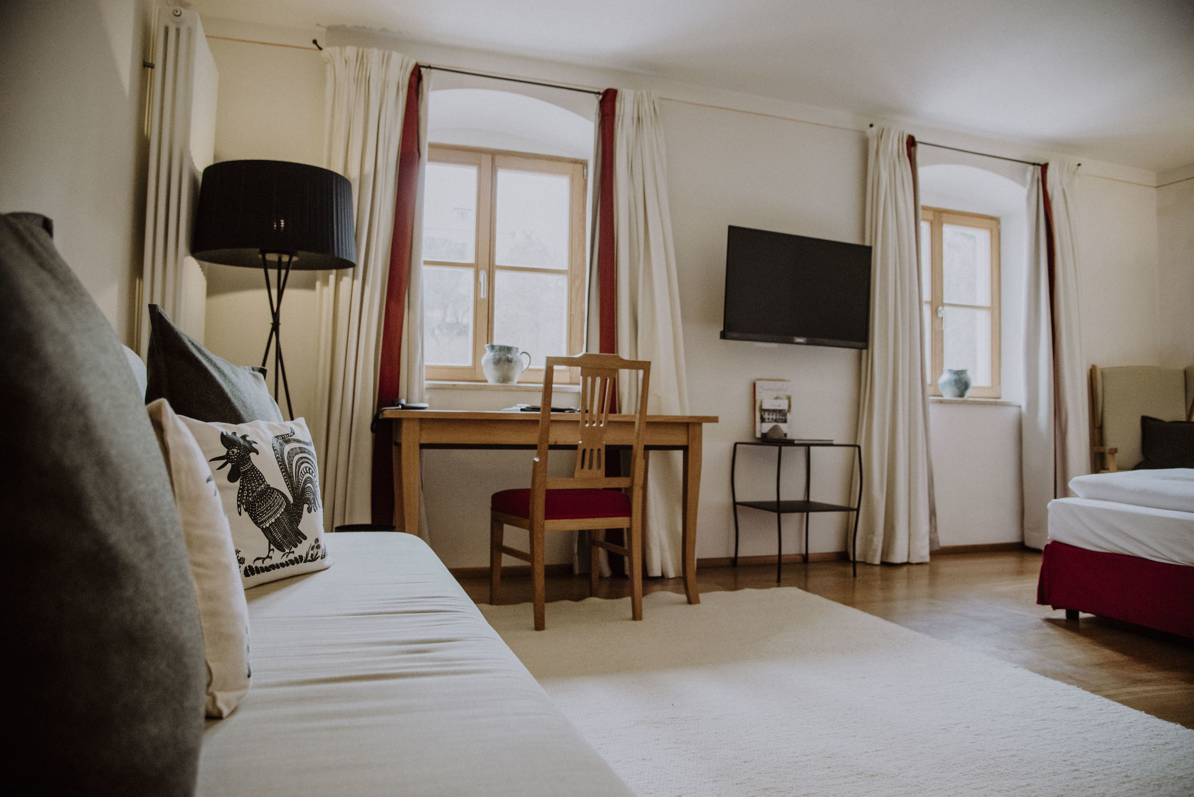 A hotel room with a bed, a desk, a chair, a TV, and curtains.