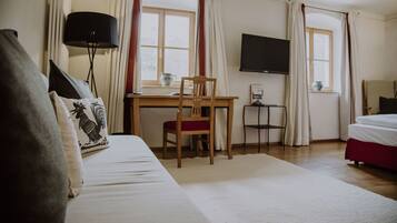 A hotel room with a bed, a desk, a chair, a TV, and curtains.