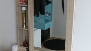 A wooden vanity with a mirror, a shelf with a bottle, and a coat hanging. - City Centre Belfast (Belfast)