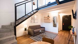 Un interior moderno con una escalera, un sofá, una mesa de centro y una alfombra estampada.