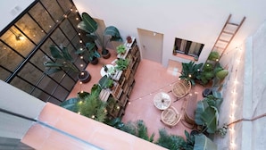 Un patio interior con zona de estar, plantas en macetas y luces colgantes.