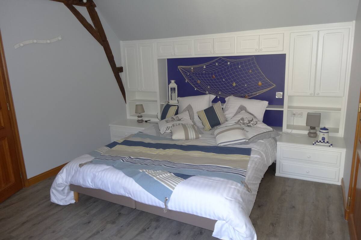 A bedroom with a bed, nightstands, a lamp, and a decorative wall piece.