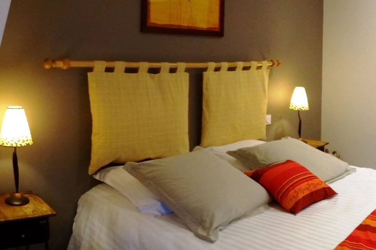 A hotel room with two beds, a wooden door, and a nightstand with a lamp.