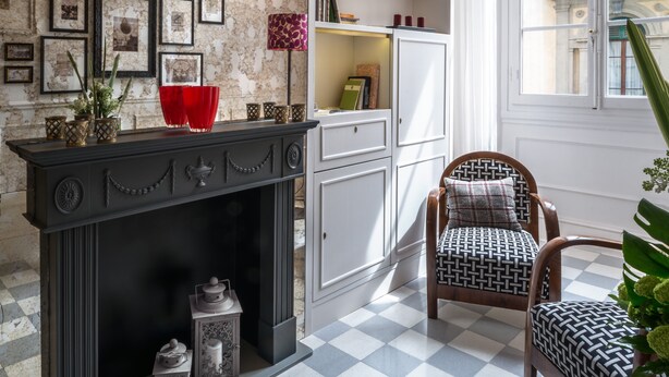 A room with a fireplace, bookshelves, framed pictures, and a window with a view of buildings. - Alfieri9 (Florence)