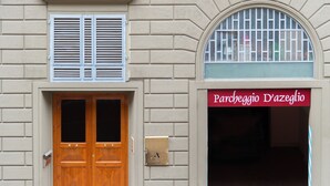 A building facade with a wooden double door, a mailbox, and a sign reading "Parcheggio D'azeglio". - Alfieri9 (Florence)