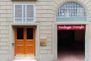 Fachada de edifício com porta dupla de madeira, caixa de correio e placa com a inscrição 'Parcheggio D'azeglio'.