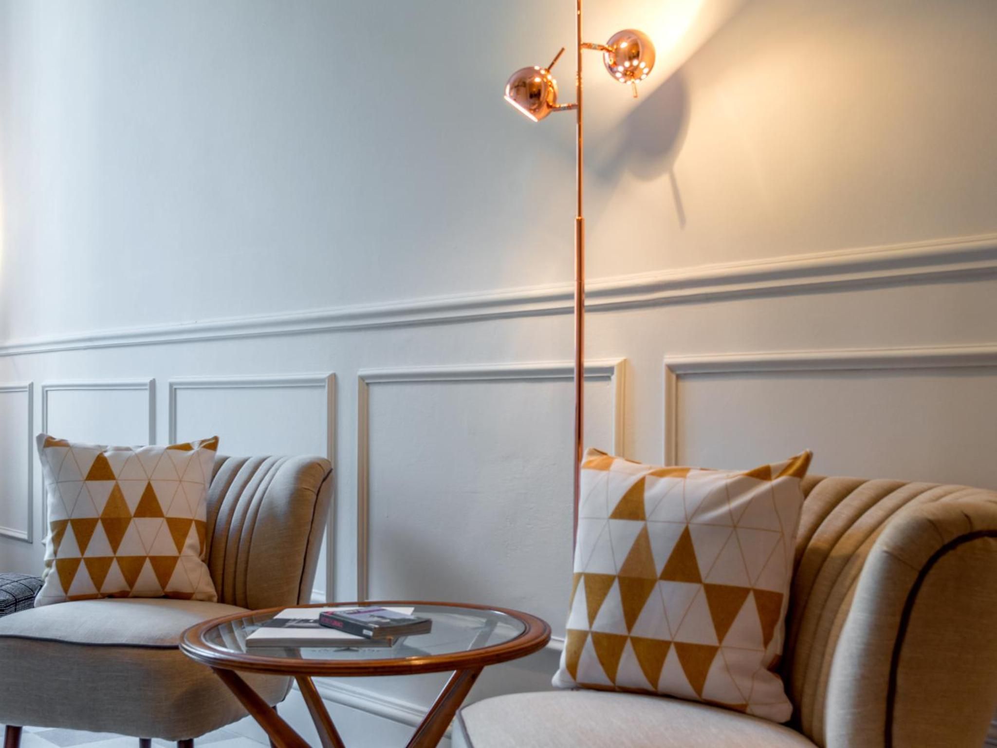 A room with a sofa, armchair, and a glass coffee table.
