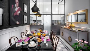 A dining area with a large table set for breakfast, a kitchen in the background, and a large framed portrait on the wall. - Alfieri9 (Florence)
