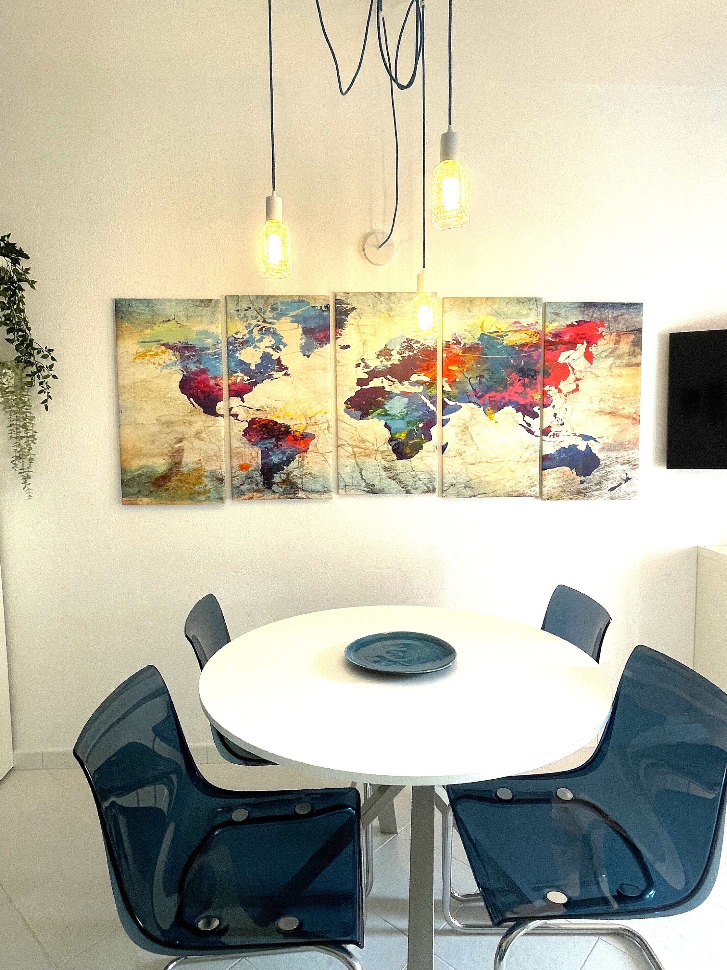 Un comedor con una mesa redonda, sillas azules y un cuadro abstracto colorido en la pared.