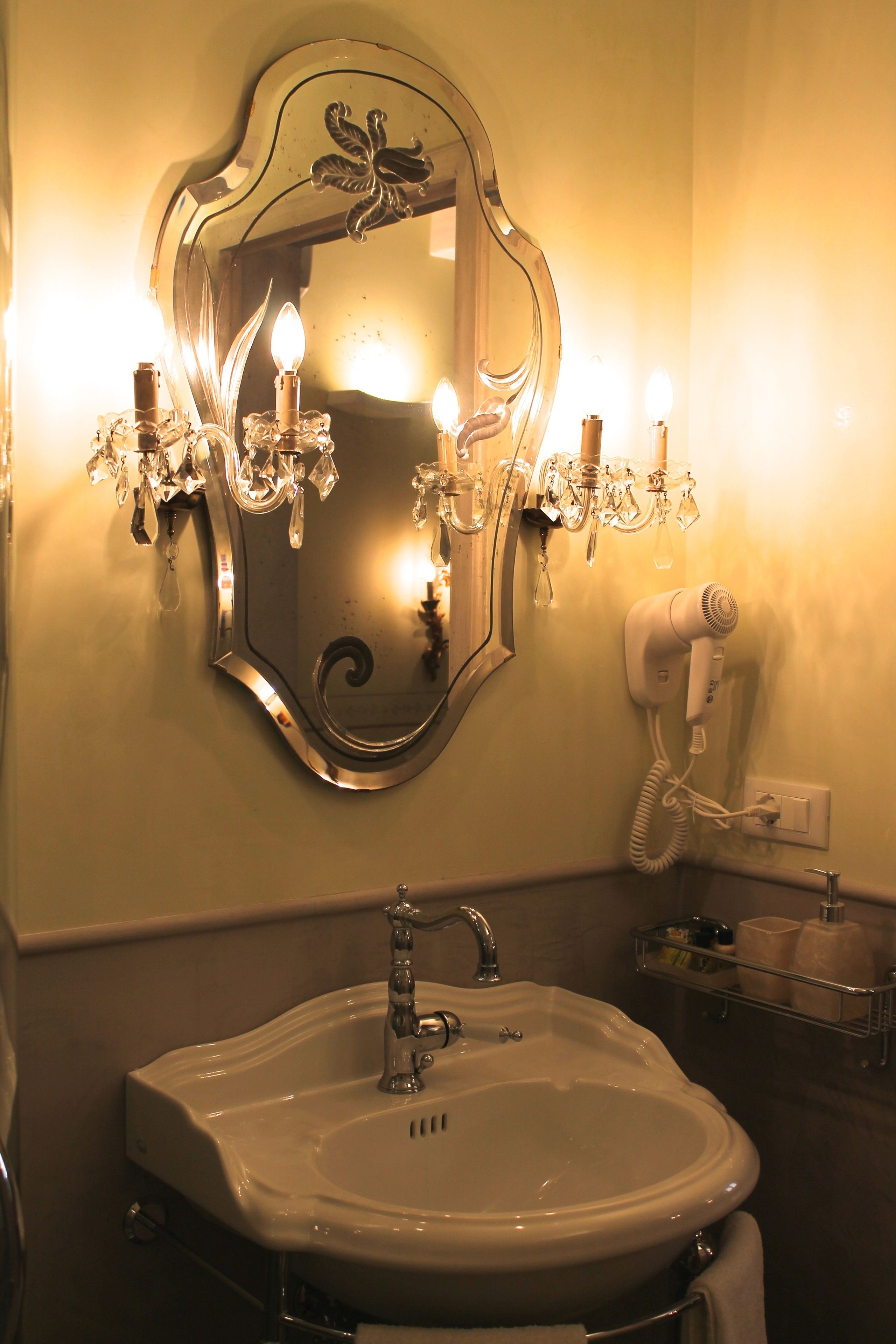 A bathroom with a large mirror, a sink, and a hairdryer on the wall.