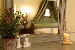 Un dormitorio con cama, una mesita de noche con vela, un espejo y una planta en maceta.