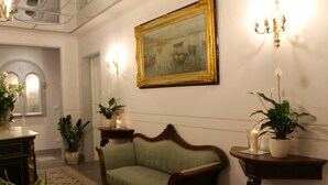 Um corredor com um sofá verde, um quadro na parede e plantas em vasos.