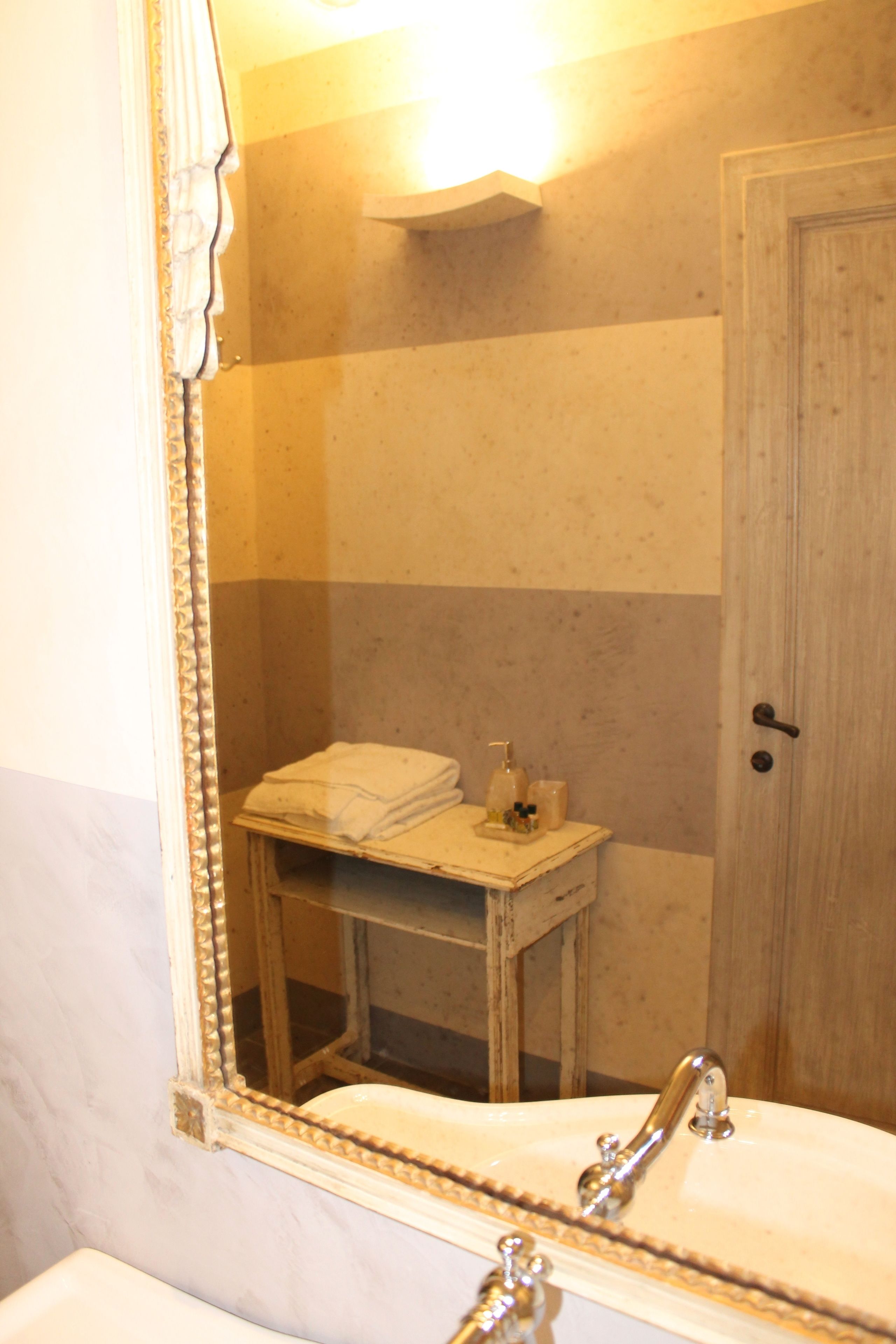 A bathroom with a sink, mirror, and a small table with toiletries.