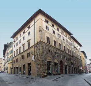 Un edificio histórico de varios pisos, con fachada de piedra y ventanas arqueadas.
