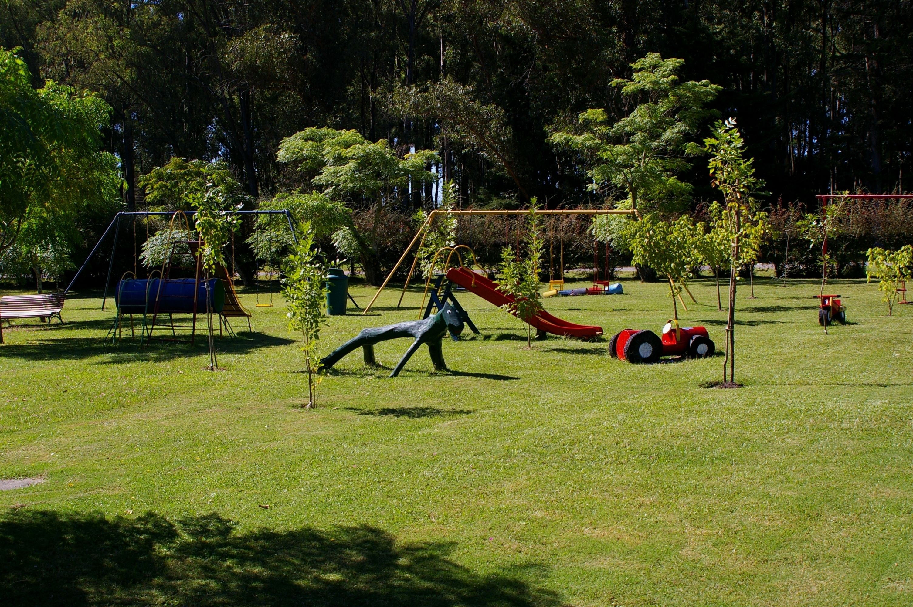 A playground with swings, slides, and a small tractor.