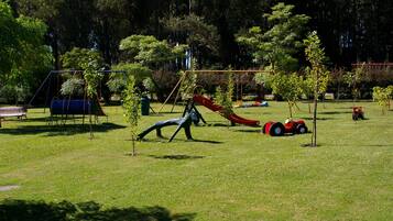 A playground with swings, slides, and a small tractor.