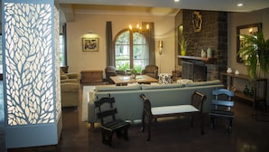 A cozy living room with a stone fireplace, comfortable seating, and a large window.