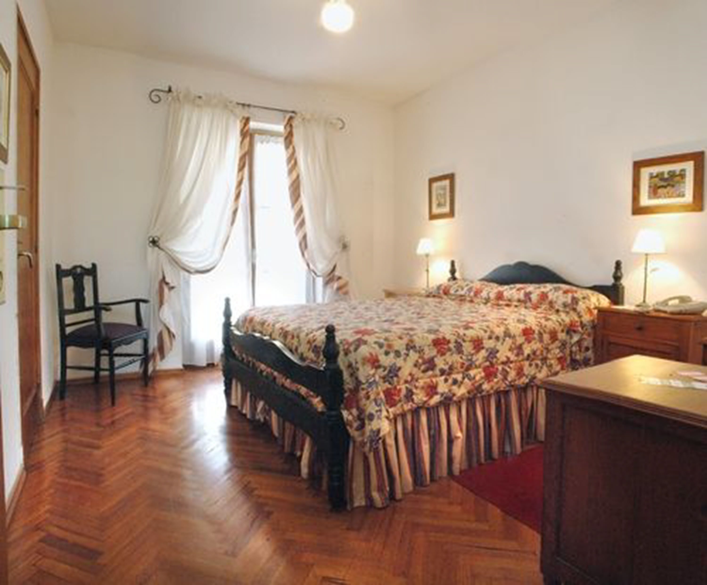 A bedroom with a bed, a chair, a desk, and a lamp.
