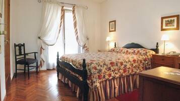 A bedroom with a bed, a chair, a desk, and a lamp.