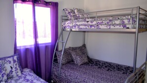 A bunk bed room with a ladder, purple curtains, and floral bedding. - Las Glorias LG104 1 Bedroom Apartment By Seaside San Carlos (San Carlos)