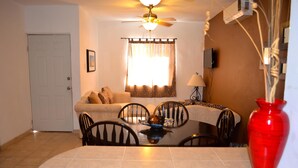 A dining area with a round table, chairs, a red vase, and a ceiling fan. - Las Glorias LG104 1 Bedroom Apartment By Seaside San Carlos (San Carlos)