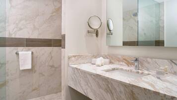 Un bagno moderno con piastrelle in marmo, box doccia in vetro, lavabo con specchio e porta asciugamani.