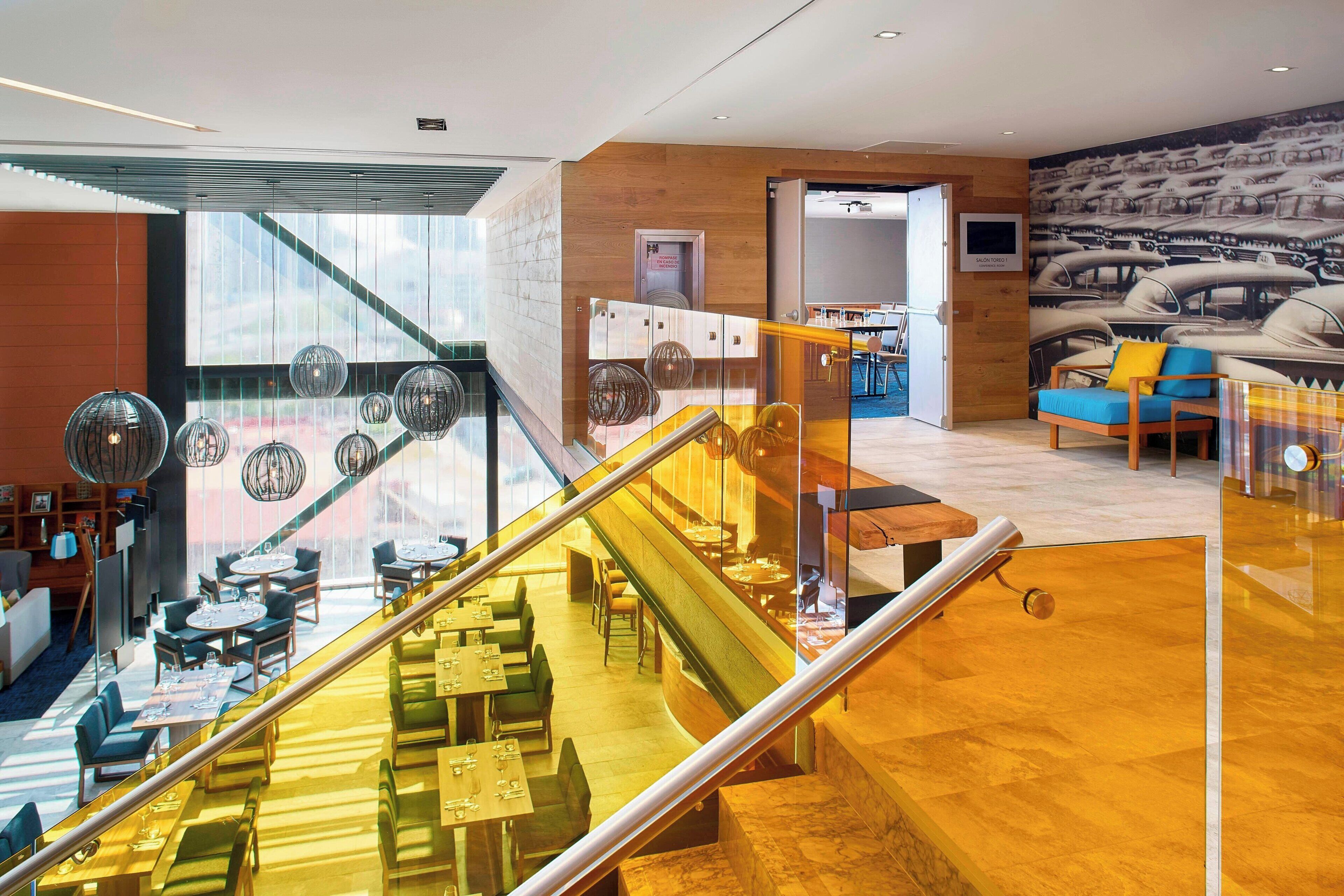 A hotel lobby with a staircase, seating area, and a mural of boats.