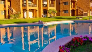 A hotel with a pool, multiple balconies, and a well-maintained lawn. - Las Glorias LG307 3 Bedroom Apartment By Seaside San Carlos (San Carlos)