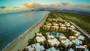 An aerial view of a coastal resort with multiple buildings, a beach, and a swimming pool. - Las Glorias LG307 3 Bedroom Apartment By Seaside San Carlos (San Carlos)