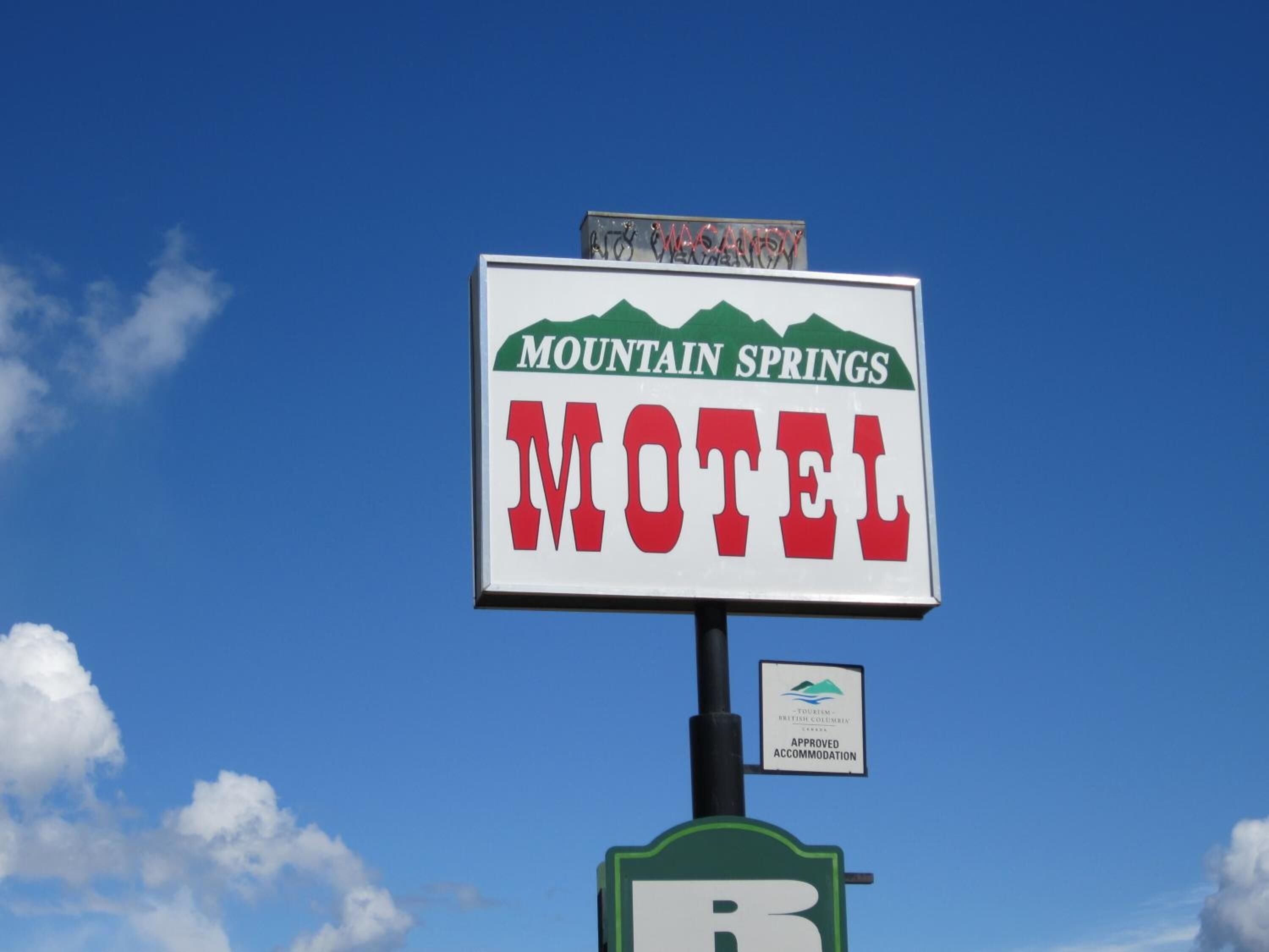 Segnaletica di motel con la scritta 'Mountain Springs', 'Motel', un simbolo 'B' e un badge 'Struttura Approvata'.