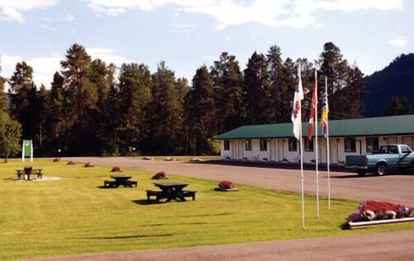 A lodge with picnic tables and a green-roofed building, surrounded by trees and mountains. - Mountain Springs Motel & RV Park (Barriere)