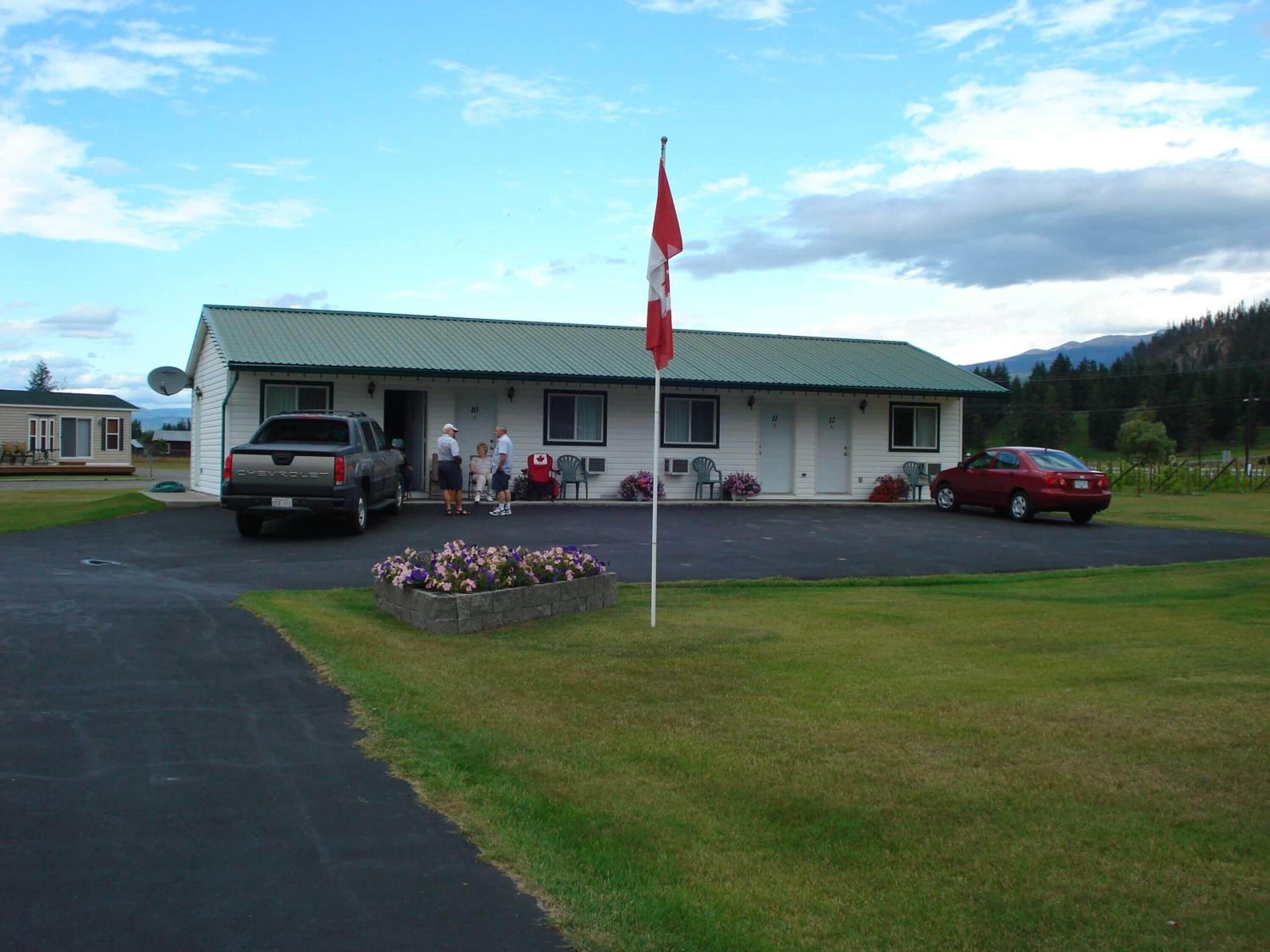 A building with a green roof and a flagpole. There are two parked vehicles in front.