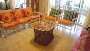 A living room with a sofa, armchairs, and a woven coffee table. - Bahia 189 Bottom Chip s Place 1 Bedroom Apartment By Seaside San Carlos (San Carlos)