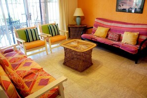 A living room with a sofa, chairs, a wicker coffee table, and a lamp. - Bahia 189 Bottom Chip s Place 1 Bedroom Apartment By Seaside San Carlos (San Carlos)