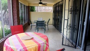 A covered patio with a table and chairs, a ceiling fan, and a view through a glass door. - Bahia 189 Bottom Chip s Place 1 Bedroom Apartment By Seaside San Carlos (San Carlos)