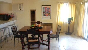 A dining area with a wooden table, four chairs, a fruit bowl, a microwave, and a potted plant. - Bahia 189 Bottom Chip s Place 1 Bedroom Apartment By Seaside San Carlos (San Carlos)
