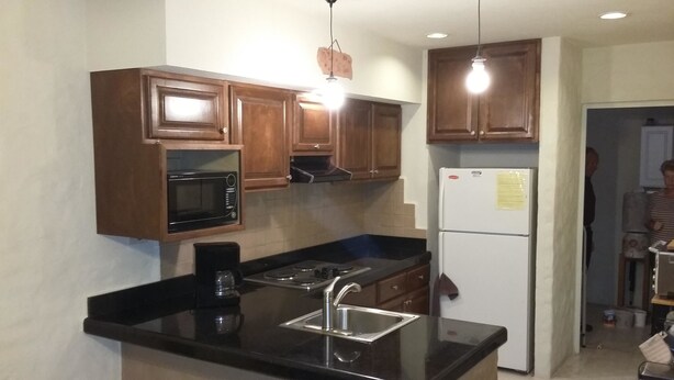 A compact kitchen with wooden cabinets, a built-in microwave, a stove, a sink, and a refrigerator. - Bahia 189 Top Chip s Place 2 Bedroom Apartment By Seaside San Carlos (San Carlos)