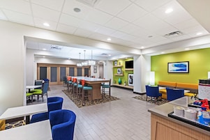 Un hall de hotel con zona de comedor, asientos y mostrador de recepción.