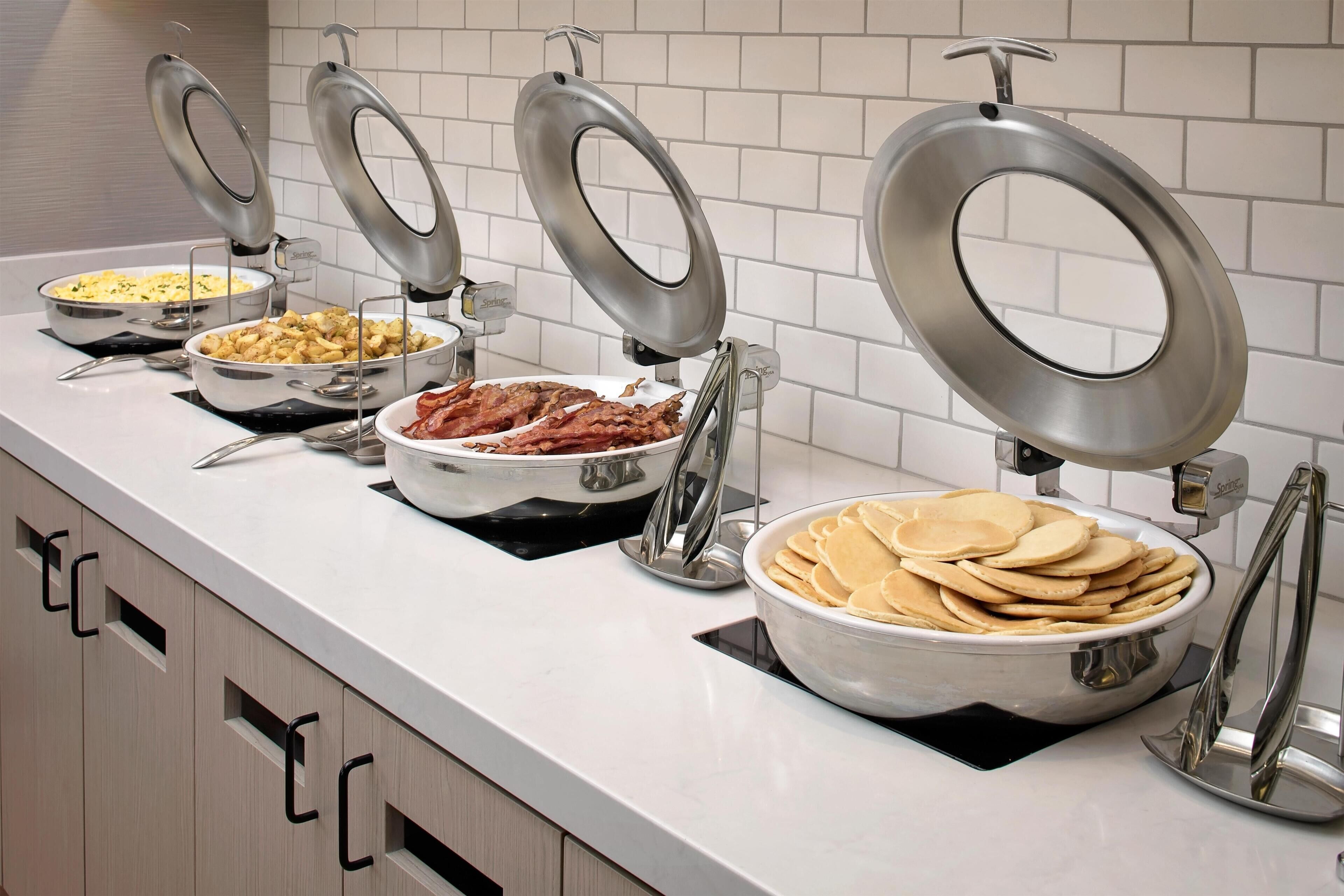A buffet setup with various food items and utensils.