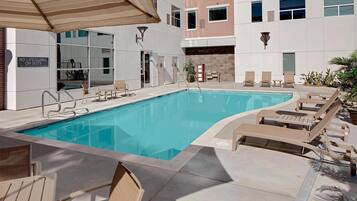 Piscina con sillas de descanso, un área techada y un cartel que indica ausencia de socorrista.