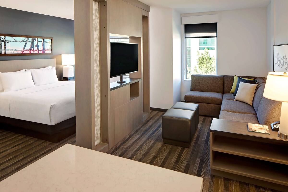 A hotel room with a bed, a TV, a sofa, and a coffee table.