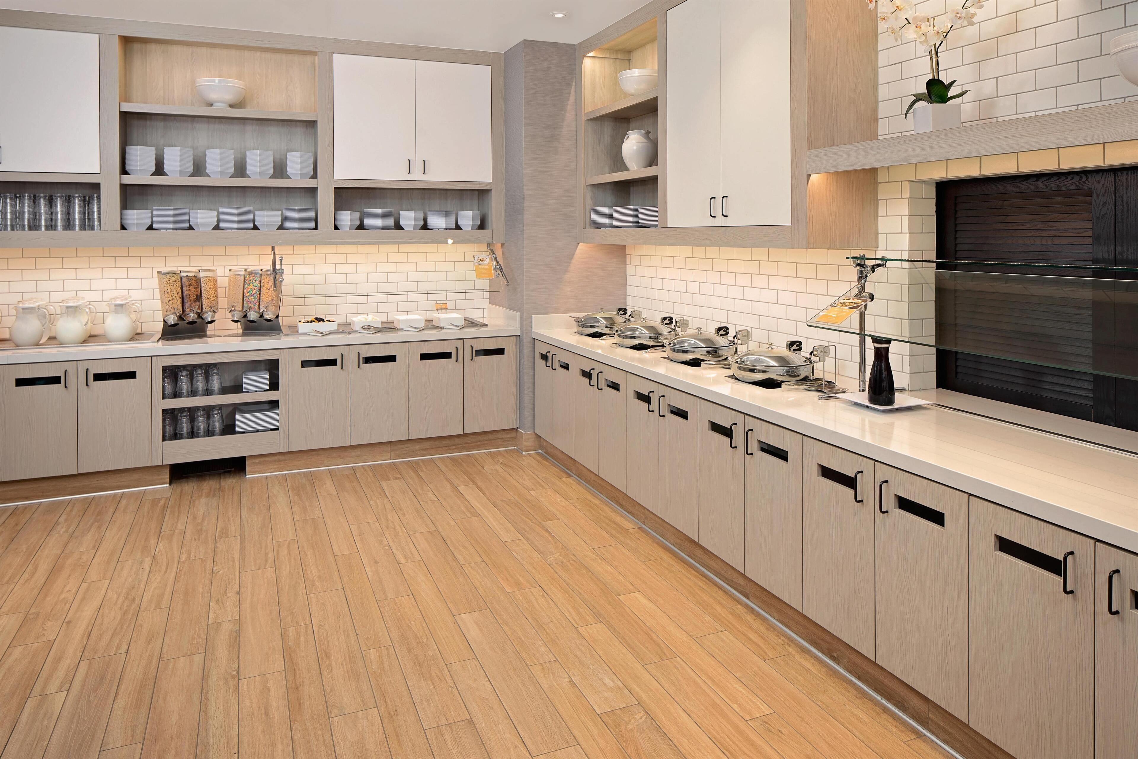 Een moderne keuken met lichte houten kastjes, witte metrotegels en roestvrijstalen apparatuur.