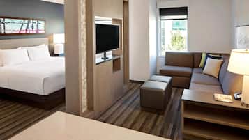A hotel room with a bed, a TV, a sofa, a coffee table, and a window with a view.