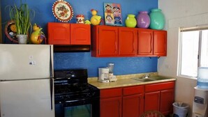 A kitchen with a white refrigerator, black stove, red cabinets, and a window with a water dispenser. - Caracol Peninsula 544 A 2 Bedroom Apartment By Seaside San Carlos (San Carlos)